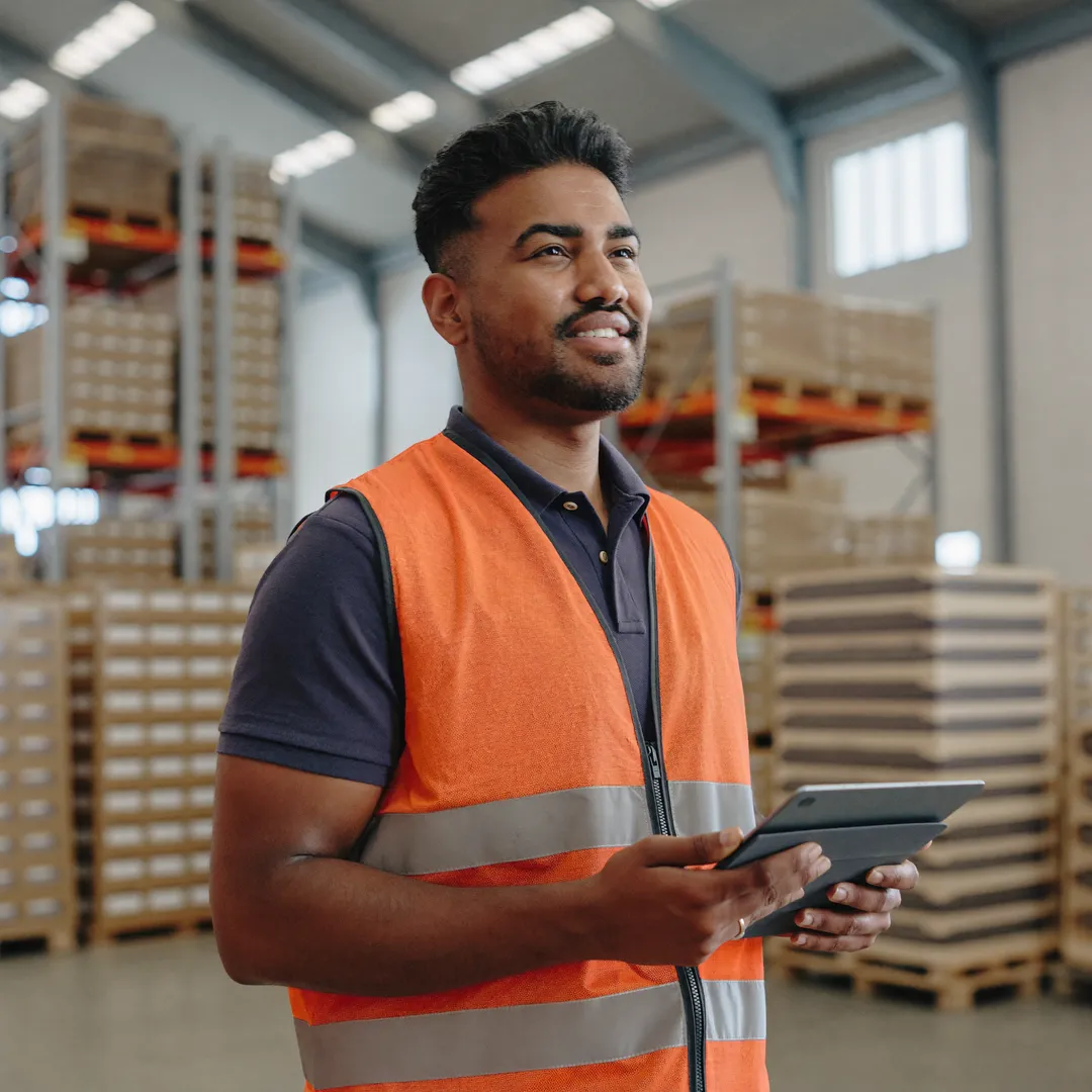 A skilled worker in a high-visibility vest in a German logistics hall